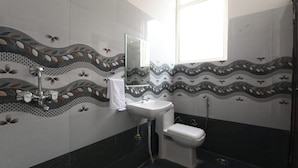 Un baño con lavamanos, inodoro y ducha. Las paredes tienen azulejos decorativos con diseño de olas.