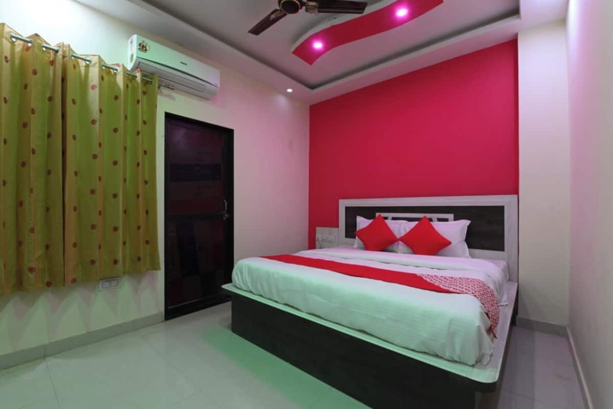Un dormitorio con cama, ventilador de techo, aire acondicionado y ventana con cortinas.