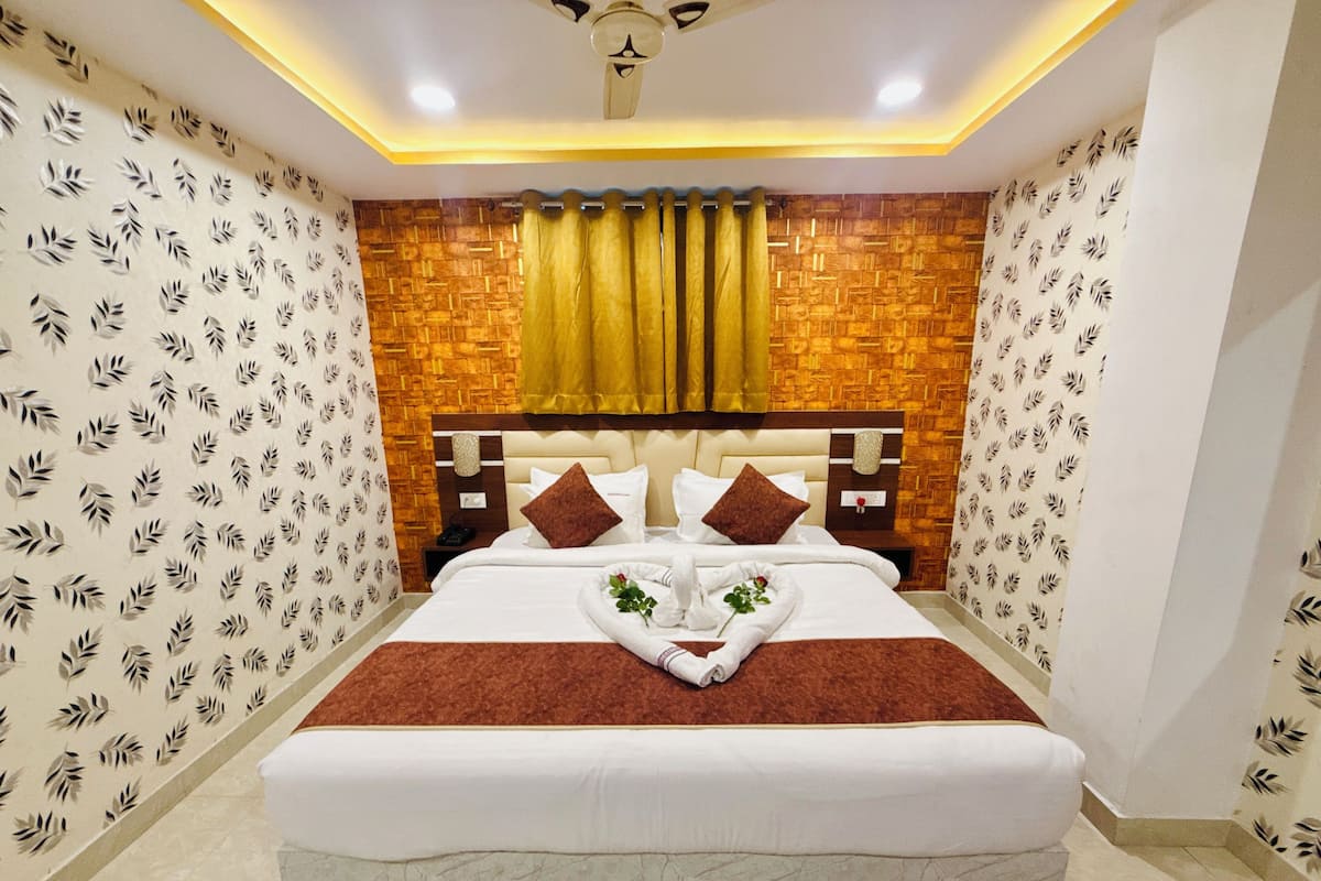 Quarto de hotel com uma cama grande, cabeceira de madeira e papel de parede estampado.