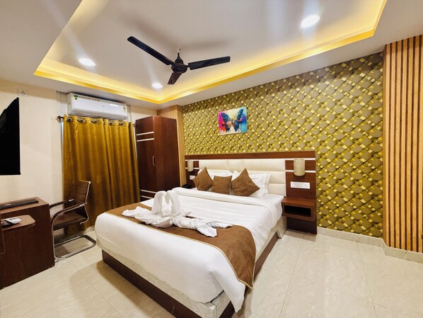 Una habitación de hotel moderna con una cama grande, un escritorio, una silla y un ventilador de techo.