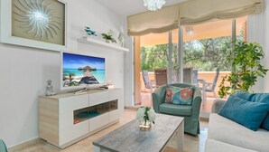 A living room with a TV, a sofa, a coffee table, and a view of the outdoors. - Apartment 'Casa Alicate' with Shared Pool, Wi-Fi and Air Conditioning (Marbella)