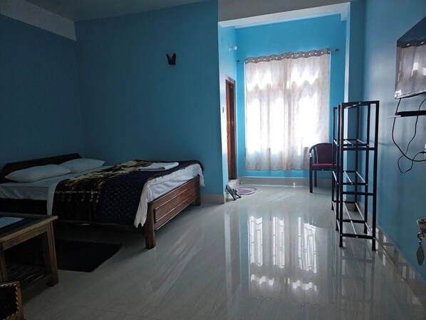A bedroom with two beds, a chair, a TV, and a shelf. - Gyalpo Homestay (Tawang)