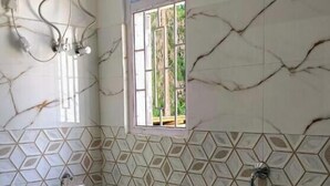 A bathroom with a toilet, a shower, and a window. - Gyalpo Homestay (Tawang)