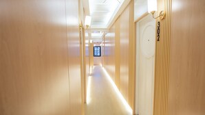 A long, narrow hallway with wooden walls and a ceiling light fixture. - Thrive Hotel (Bangkok)