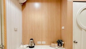 A compact kitchenette with a built-in refrigerator, a coffee maker, and a small countertop. - Thrive Hotel (Bangkok)