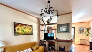 A living room with a sofa, coffee table, TV, fireplace, and artwork.