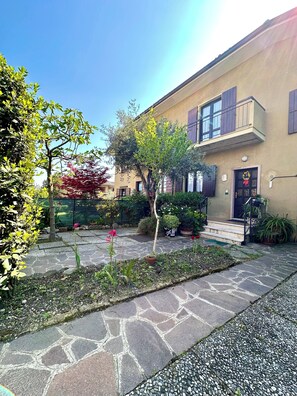 Ein Innenhof mit einem gepflasterten Weg, einem kleinen Baum und einem Gebäude mit einem Balkon.