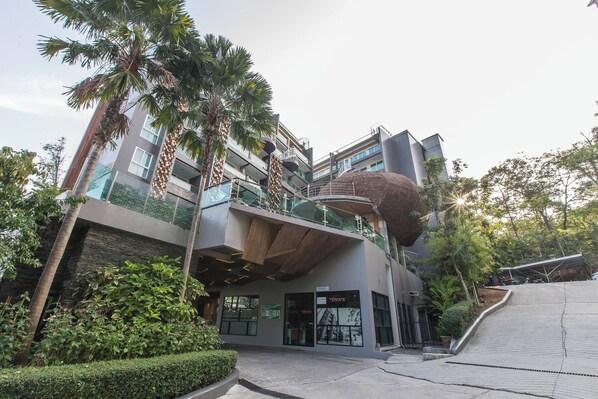 A modern multi-story building with balconies, a unique spherical structure, and a well-maintained garden area.