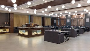 Un restaurant moderne doté d'un comptoir central où sont exposés les plats, entouré de tables et de chaises.