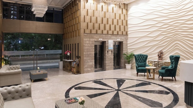 Un hall d’entrée moderne doté d’un motif circulaire au sol, d’un comptoir d’accueil et de plusieurs espaces aménagés pour s’asseoir.