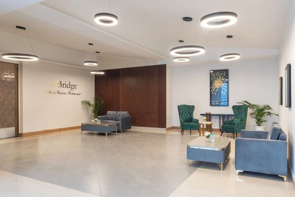 A modern lobby with a reception desk, seating area, and a large painting on the wall. - Ginger Ghaziabad, Raj Nagar Extension (Ghaziabad)