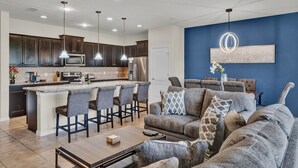 A modern kitchen with dark cabinets, a central island with bar stools, and pendant lighting.