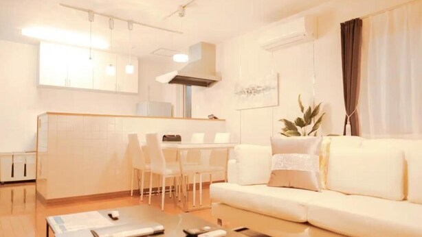 A modern living room with a sofa, a coffee table, and a dining area with chairs and a table. - Familia Design House Sapporo (Sapporo)