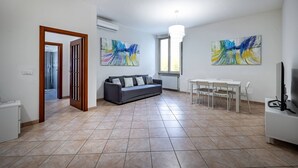Un soggiorno con un divano, un tavolo da pranzo con sedie e quadri astratti alle pareti.