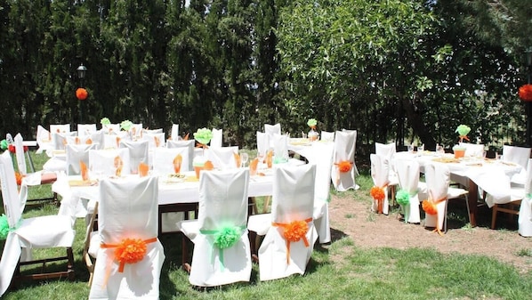 Un événement en plein air, avec des tables et des chaises, dont certaines sont décorées de couleurs orange et verte.
