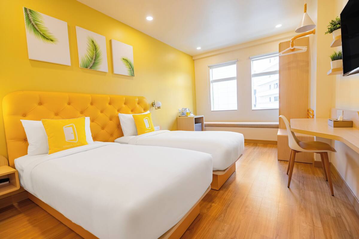 Habitación de hotel con dos camas, un escritorio y una silla.