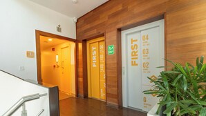 Eine Hotelhalle mit Holzwandverkleidung, nummerierten Türen zu den Zimmern und einer Rezeption.