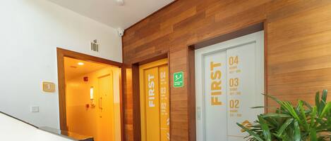 Un hall de hotel con paneles de madera, puertas numeradas que dan a las habitaciones y una zona de recepción.