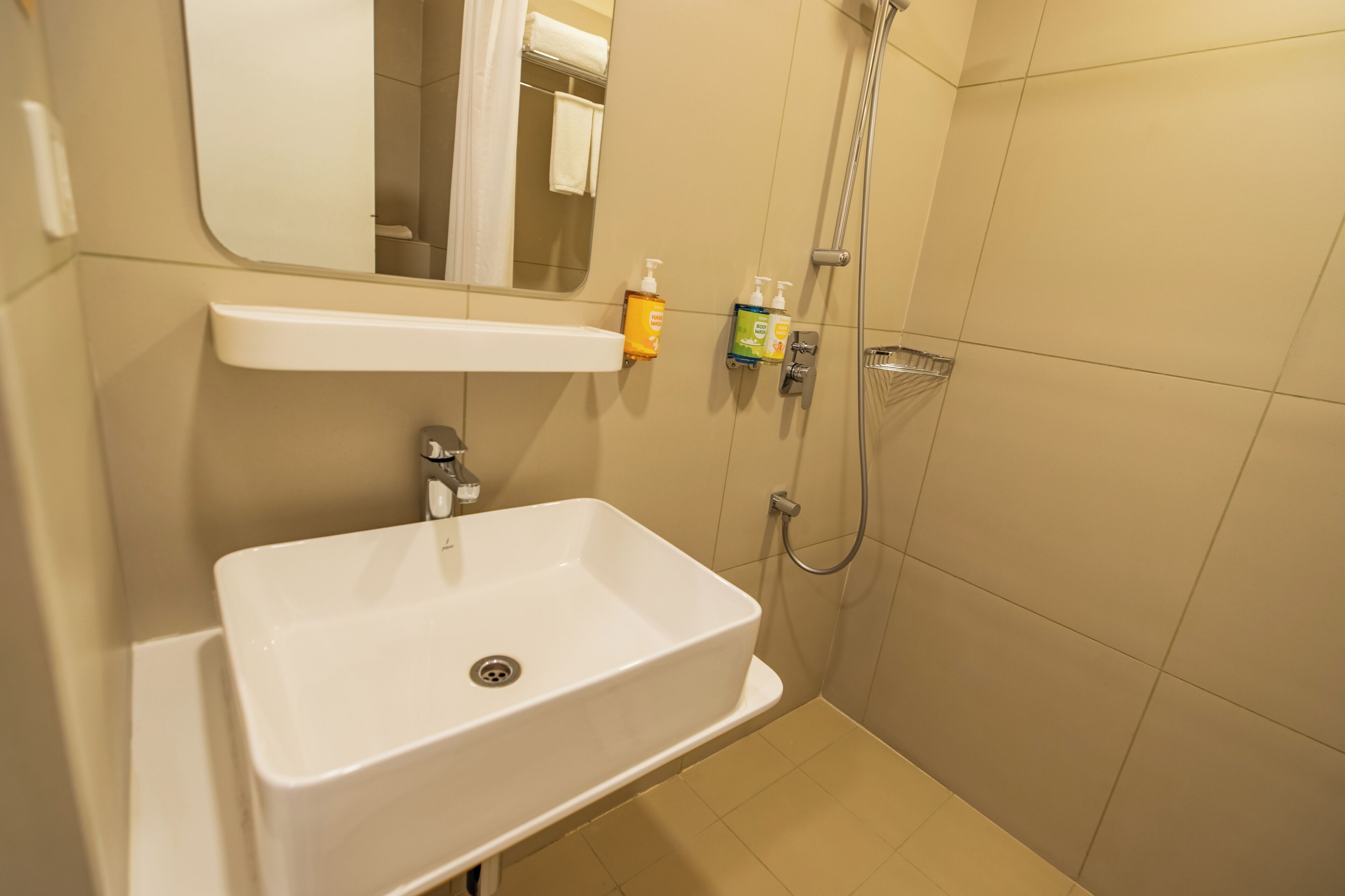 A bathroom with a white sink, a mirror, a shower, and toiletries on the wall.