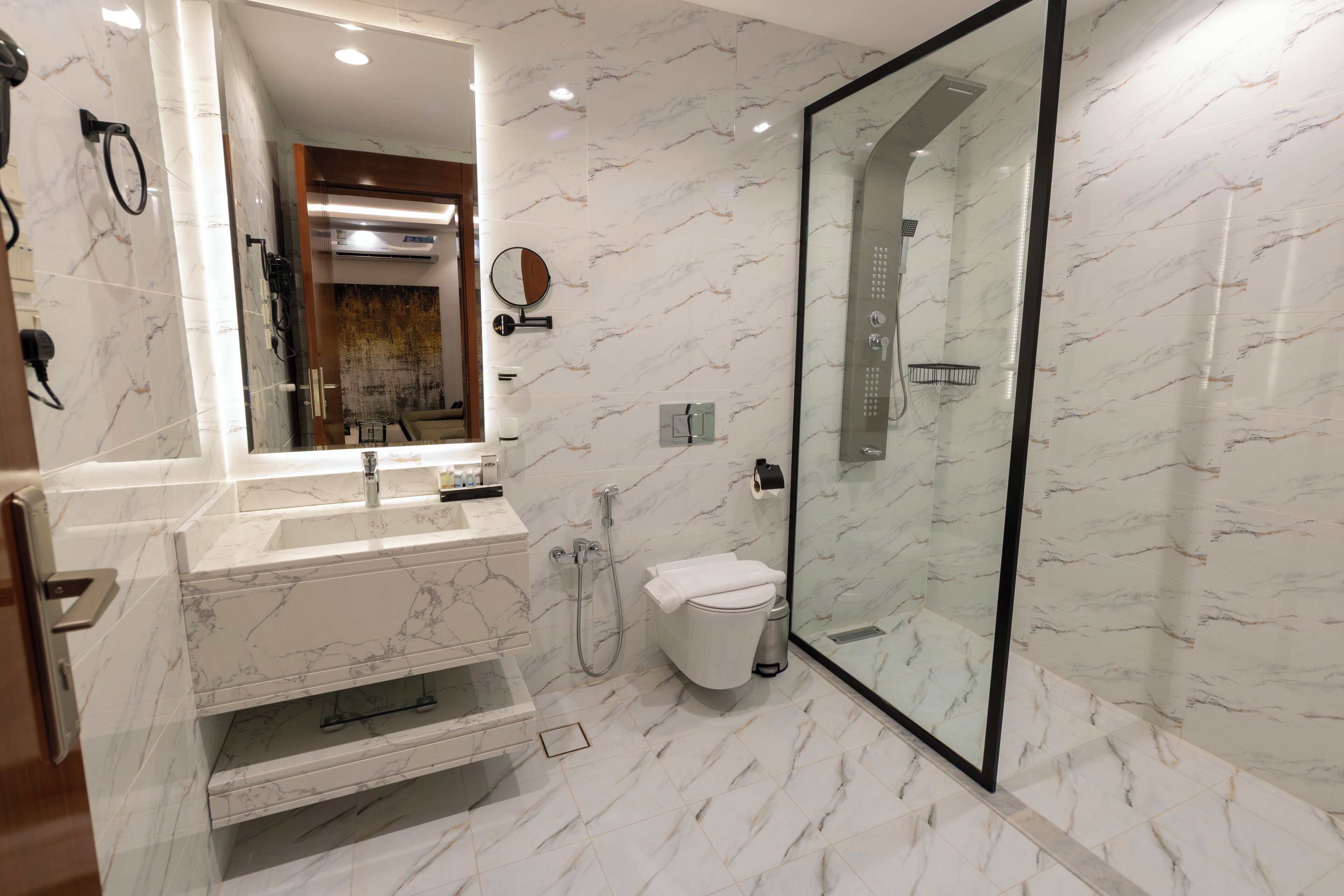 A modern bathroom with a marble sink, toilet, and glass-enclosed shower.