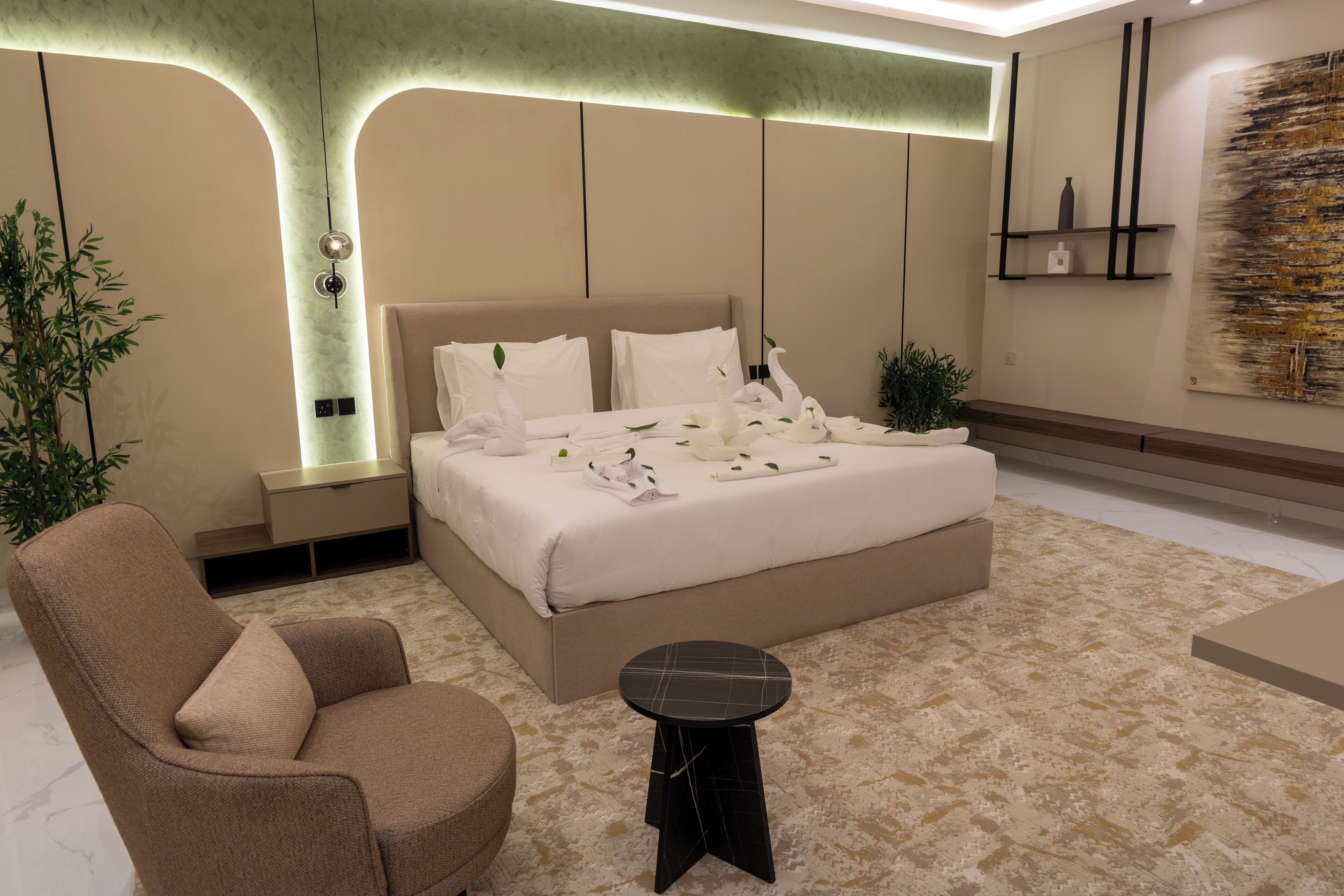 Un dormitorio moderno con una cama grande, una mesita de noche, una silla, una pequeña mesa y un estante montado en la pared.
