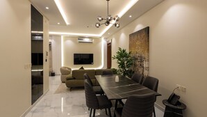 A modern dining area with a marble floor, a long table, and dark chairs. - Luxury suites Hotel Apartments (Taif)