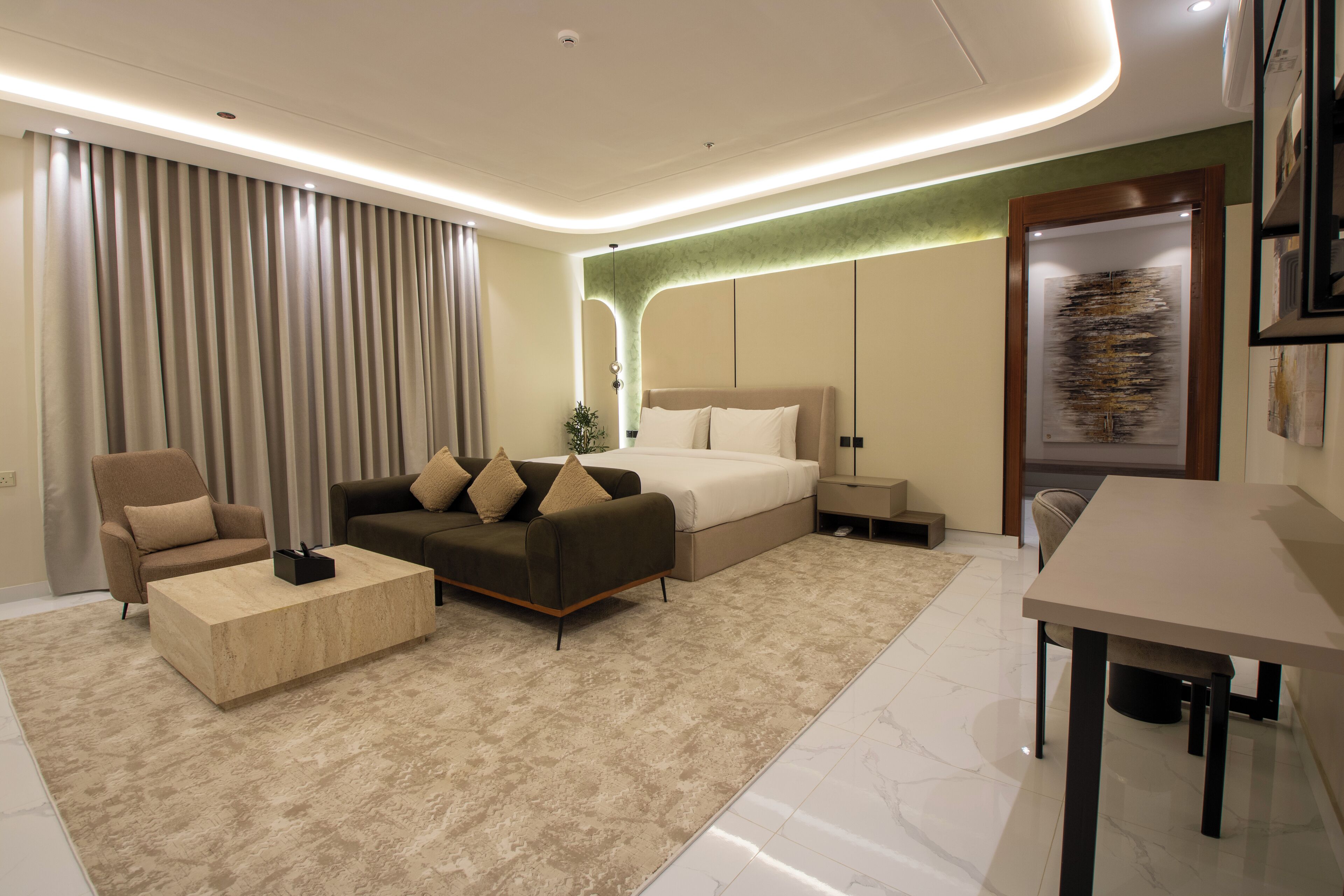 Ein modernes Hotelzimmer mit Bett, einer Couch, einem Couchtisch und einem Essbereich.