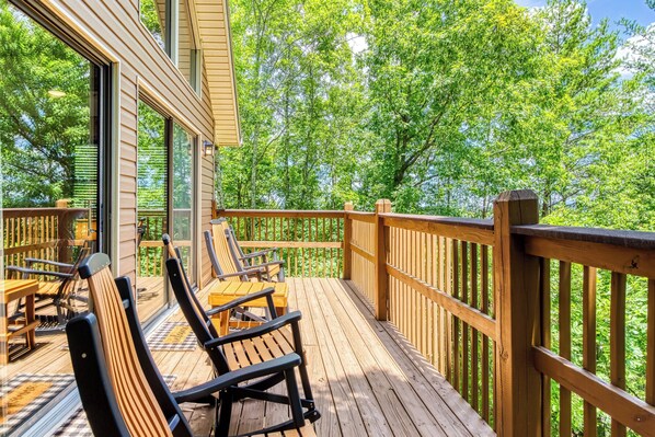 Une terrasse en bois avec des sièges extérieurs et une vue sur les arbres.