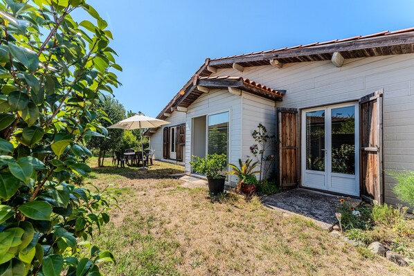 A house with a patio, a dining table, and potted plants.