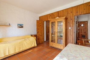 Une pièce avec un lit, une armoire en bois et un sol carrelé.