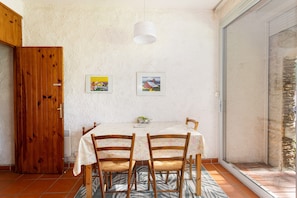 A dining area with a table, chairs, and two framed pictures on the wall. - Argelès Plage Apartment – Mountain View & Balcony, 300 m from the Beach (Argelès-sur-Mer)