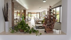 Un ambiente spazioso con zona pranzo, ampie finestre e un modellino di nave decorativo.