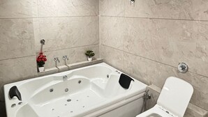 Een moderne badkamer met een groot bad, een toilet en een douchekop.