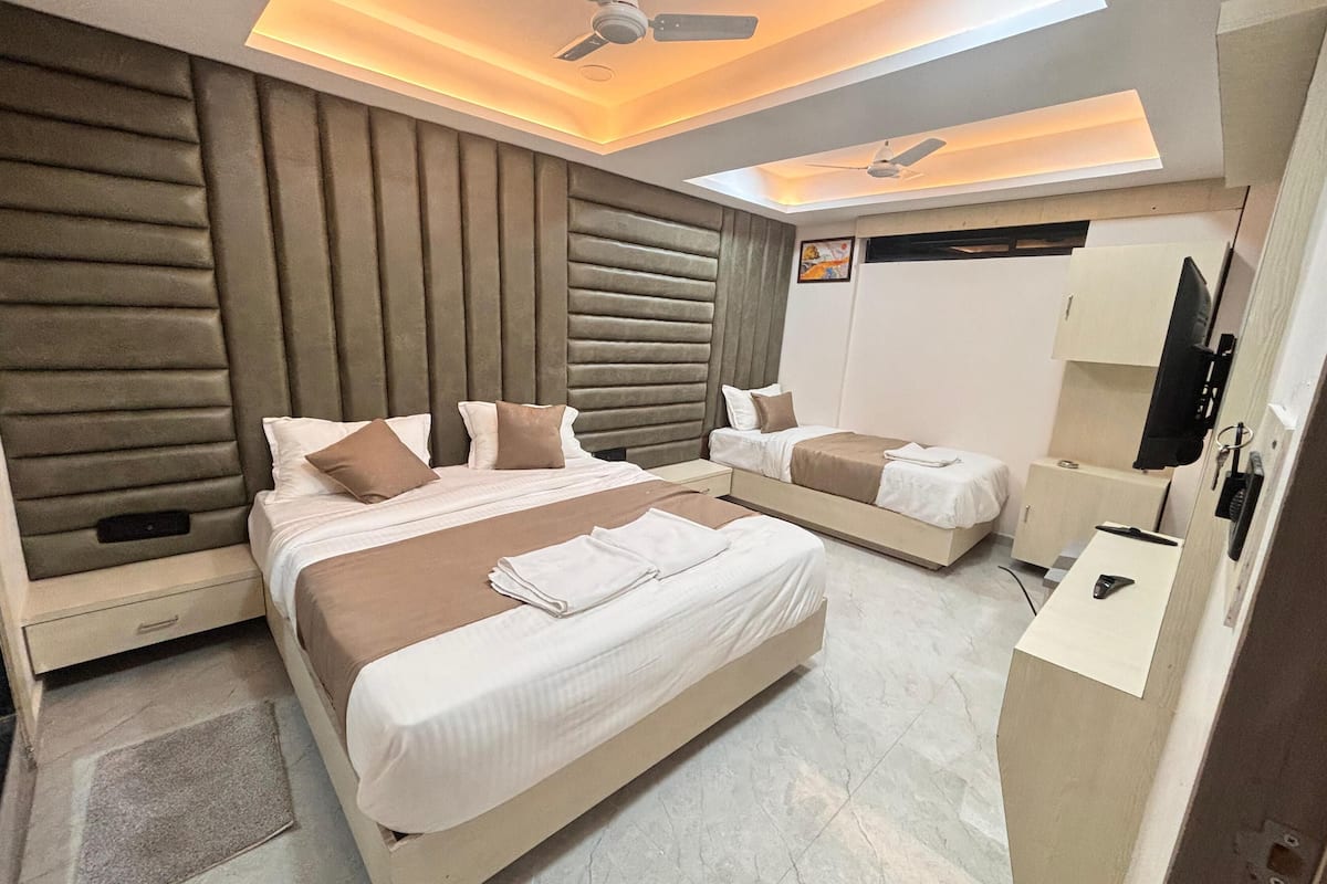A modern hotel room with a large bed, a smaller bed, a desk, and a ceiling fan.