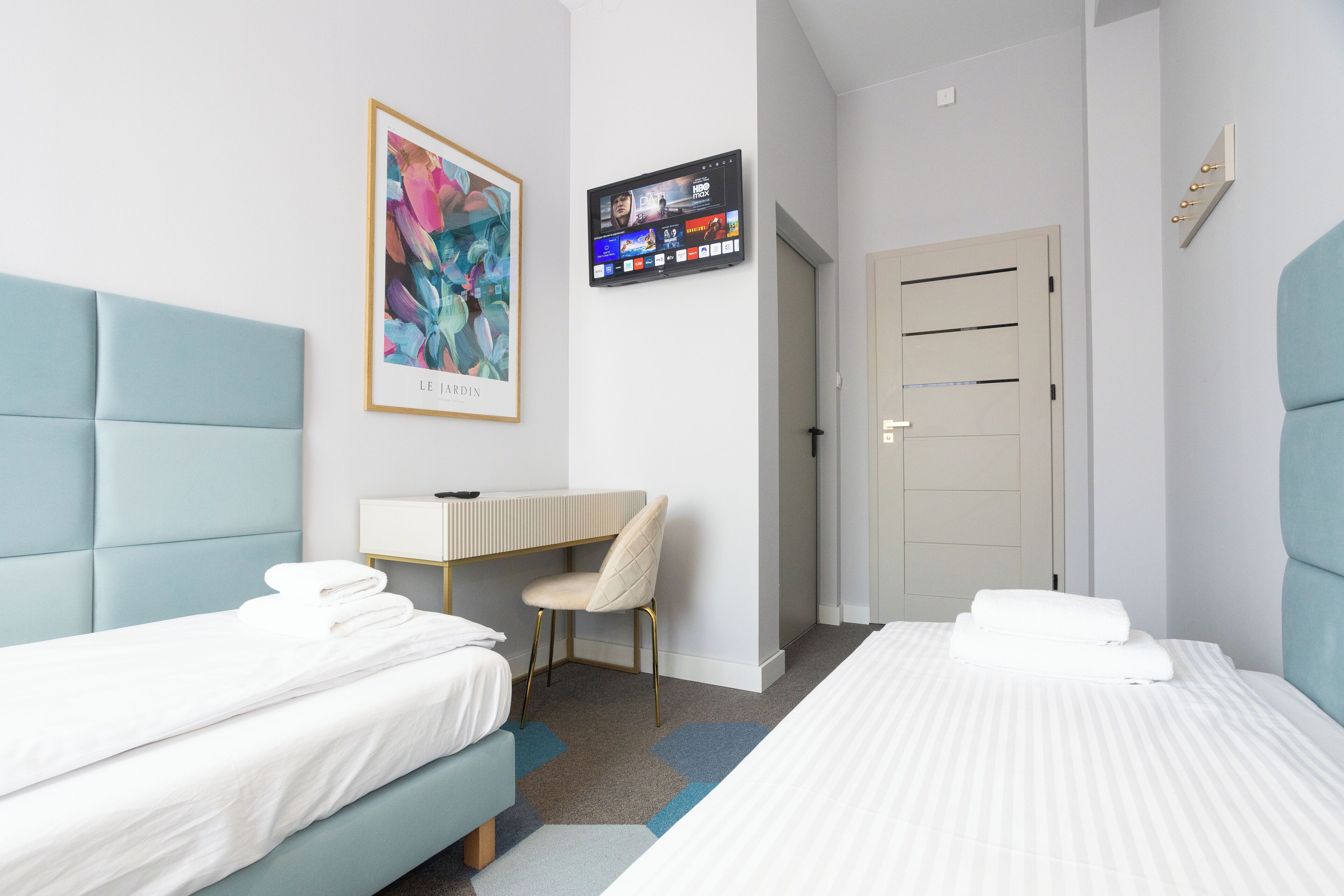 Une chambre d’hôtel avec deux lits, un bureau, une chaise, une télévision et une porte.