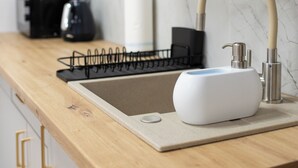 A kitchen with a marble countertop, a sink with a modern faucet, and wooden cabinets. - Moon ApartHotel (Wrocław)