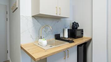 Een moderne keuken met een houten aanrecht, een spoelbak, een magnetron en een waterkoker.
