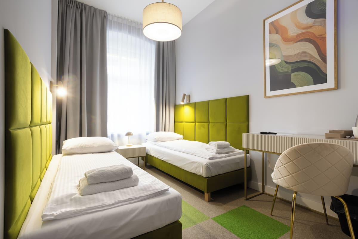 A hotel room with two beds, a desk, and a chair.