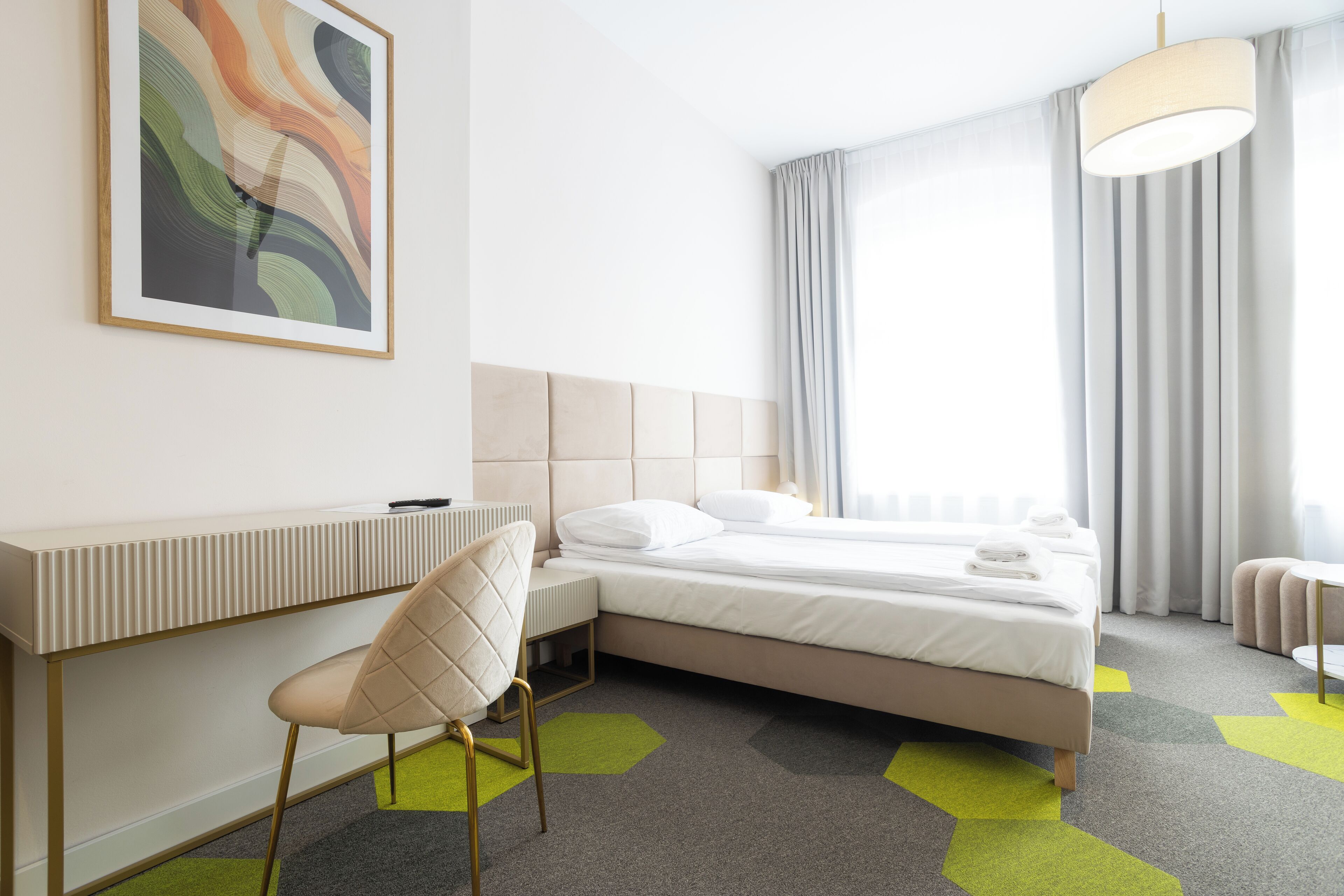 Une chambre d’hôtel moderne, équipée d’un lit, d’un bureau et d’une chaise.