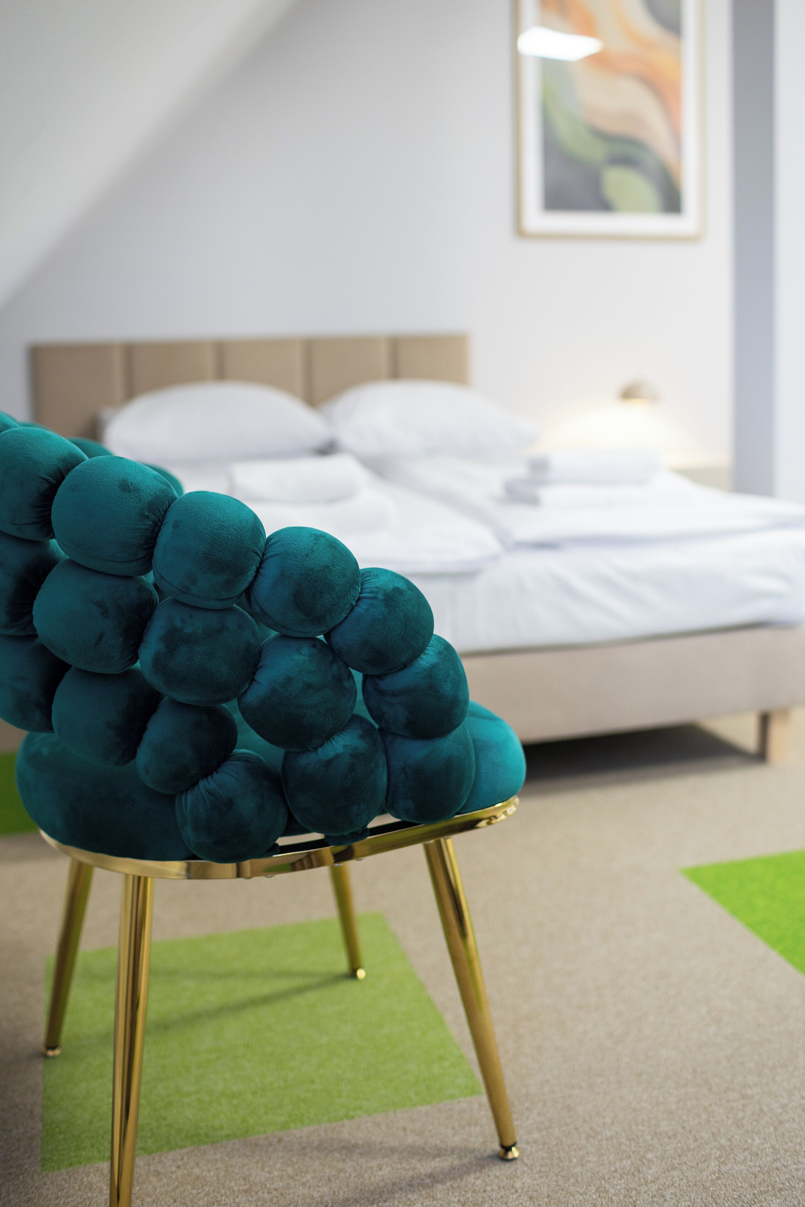 A teal upholstered chair with gold legs in a hotel room.