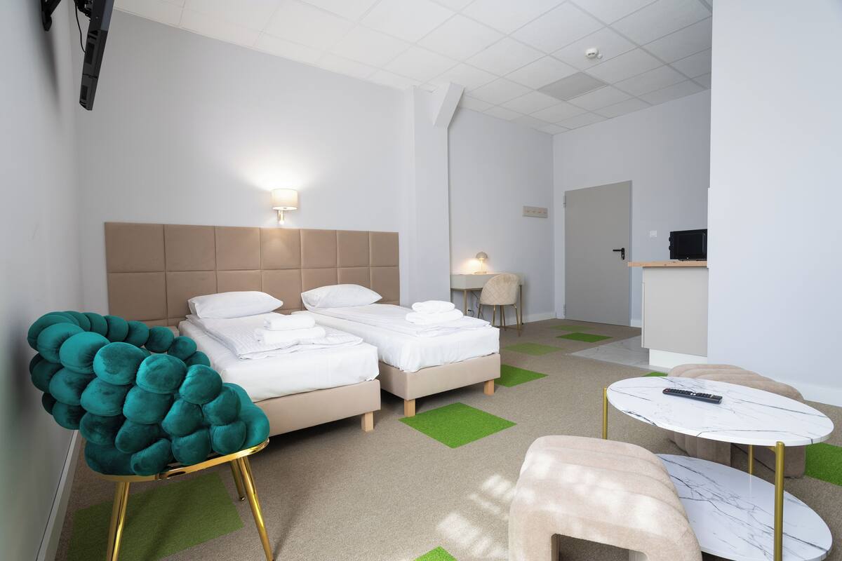 A hotel room with a bed, a chair, a small table, and a desk.