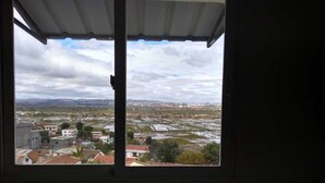 Vista desde una ventana sobre un paisaje urbano con edificios y campos abiertos.
