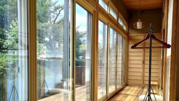 Una habitación con amplios ventanales, suelo de madera y un perchero.