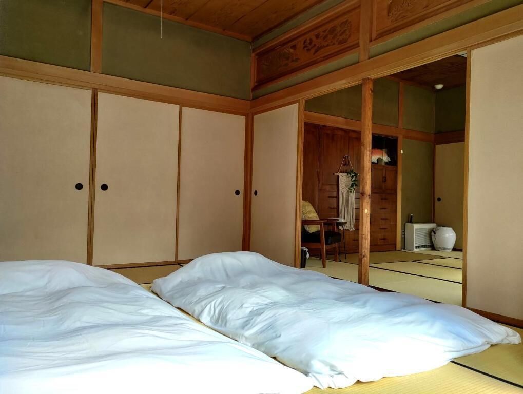 A traditional Japanese-style room with tatami flooring, a bed with white bedding, and sliding doors.