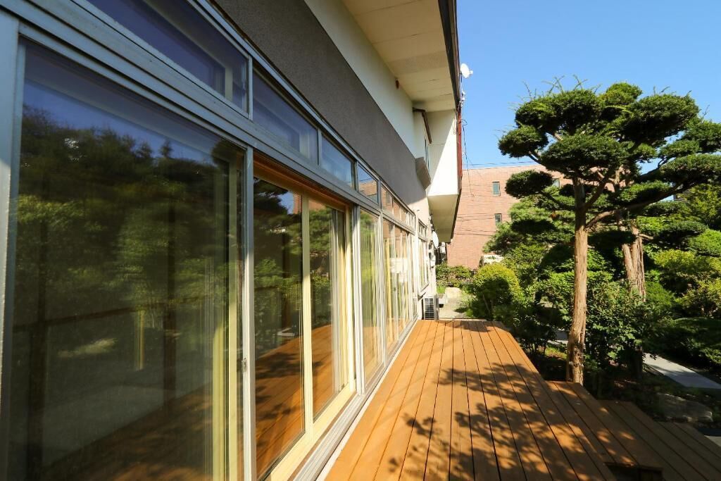 Un edificio moderno con amplios ventanales de vidrio y una terraza de madera.