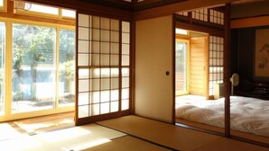 Una habitación japonesa tradicional con suelo de tatami, puertas correderas y una cama.