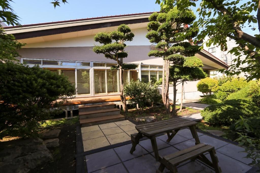 A modern building with a glass facade, surrounded by well-maintained greenery and a wooden bench.
