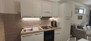 A compact kitchen with a sink, stove, and cabinets, a dining area with a table and chairs, and a window with a view.
