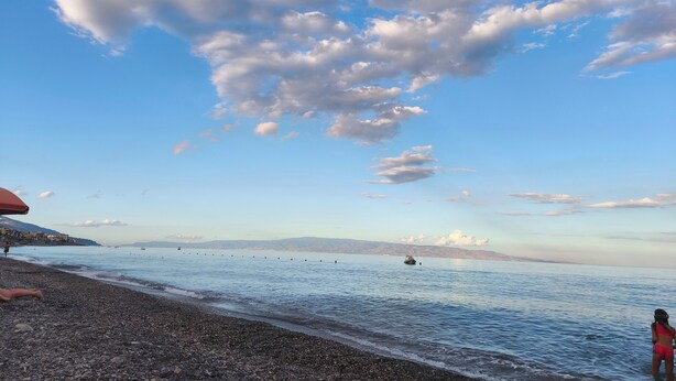 A pebbled beach with calm water, a clear sky, and distant mountains. - The Sisters a stone's throw from Taormina (Santa Teresa di Riva)