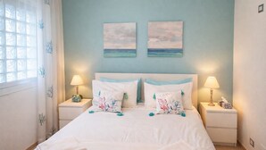 A bedroom with a bed, two nightstands, lamps, a window with curtains, and two wall art pieces. - The Sisters a stone's throw from Taormina (Santa Teresa di Riva)